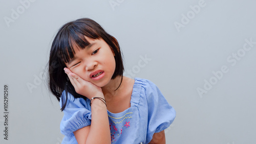 Asian kid girl toothache. Kid suffering from toothache. Asian child hand on cheek face as suffering from facial pain, mumps toothache. Dental health care.