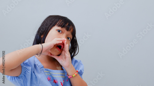 Little asian girl kid wearing casual clothes shouting out loud with hands over mouth photo