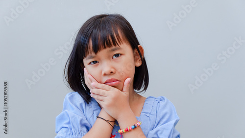 Asian kid girl toothache. Kid suffering from toothache. Asian child hand on cheek face as suffering from facial pain, mumps toothache. Dental health care.