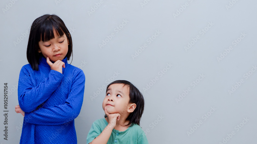 two children standing together and looking to each other holding their chin. two children standing together and looking to each other holding their chin.