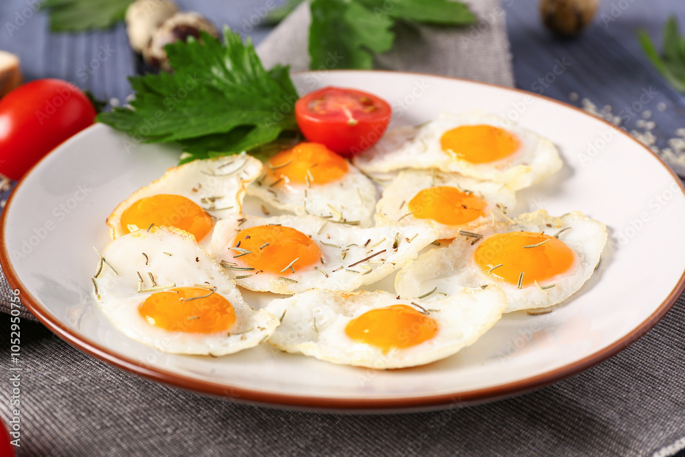 Plate with fried quail eggs, parsley and tomatoes on blue wooden background Plate with fried quail eggs, parsley and tomatoes on blue wooden background