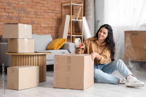 Photos Beautiful woman taping box in room on moving day