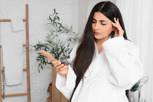 Hair loss and alopecia concern, woman in bathrobe looking at hair on brush wi...