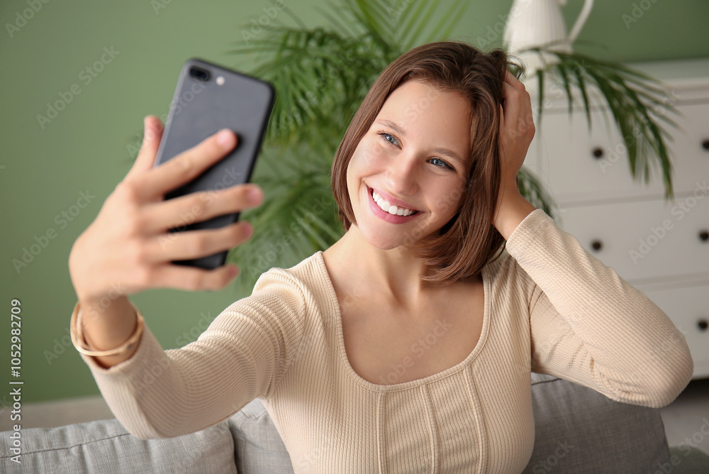 Pretty young woman with mobile phone taking selfie on sofa at home Pretty young woman with mobile phone taking selfie on sofa at home
