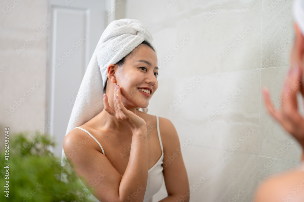 A beautiful Asian woman is touching her face and looking into the mirror in the bathroom. A beautiful Asian woman is touching her face and looking into the mirror in the bathroom.