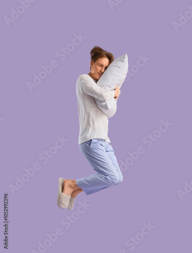 Jumping young man in pajama...