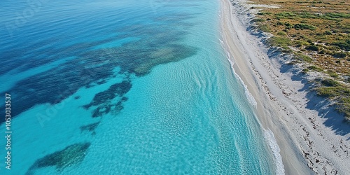 Aerial view of a beautiful white sandy beach with crystal clear turquoise water and coral reefs.