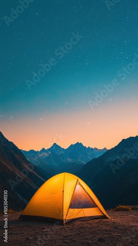 A bright yellow tent set against a stunning mountain backdrop at sunset.