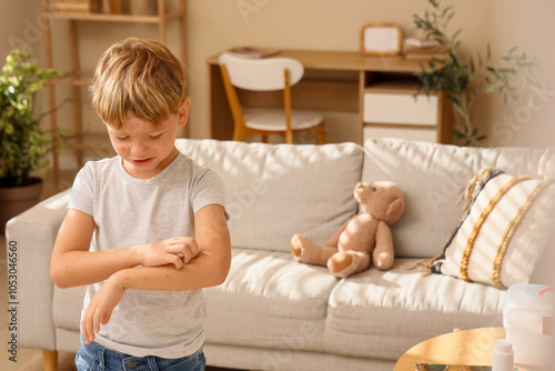 Little boy ill with chickenpox scratching his arm at home