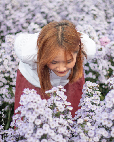 Beautiful asia woman bending down to look at flowers in the field