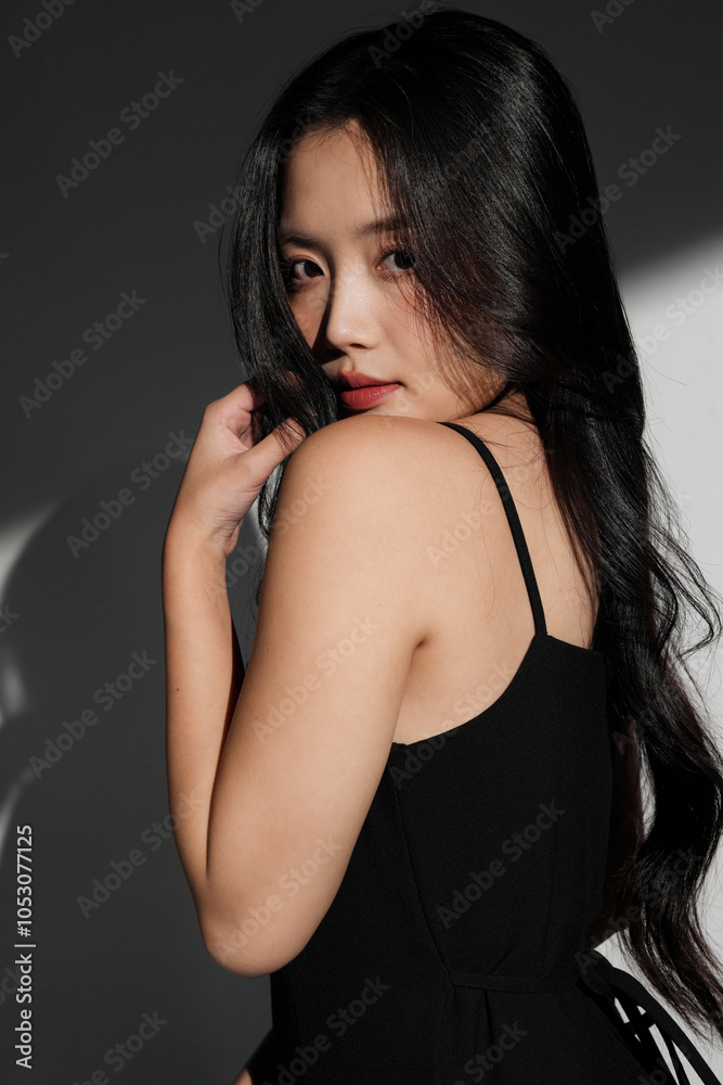 光と影の背景で撮影をした黒いドレスを着た若い女性のシックなポートレート
