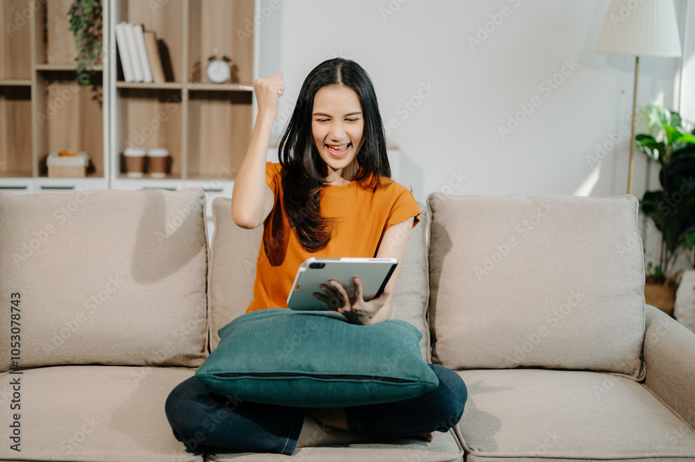 Obraz premium Asian woman using the smartphone and tablet on the sofa at home.