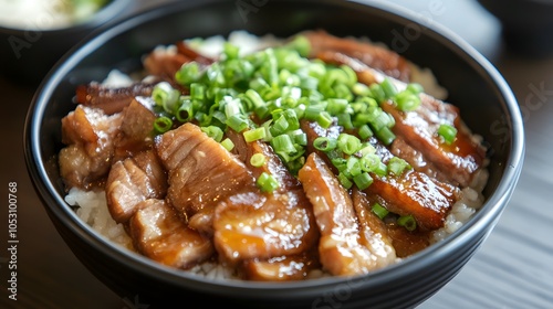 A bowl of chashu don, rice topped with slices of braised pork belly and green onions.