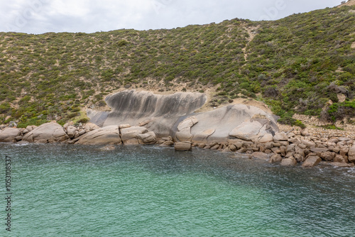 Beautiful aquamarine water below a granite headland with vegetation, bare granite rock and boulders and a man made old wall at the water's edge in Stenhouse Bay on Yorke Peninsula in South Australia. photo