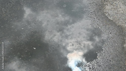 4K Closeup of light rain drops falling on puddle