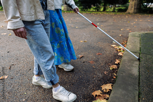 Behang Blind woman using white cane walking in a park with friend
