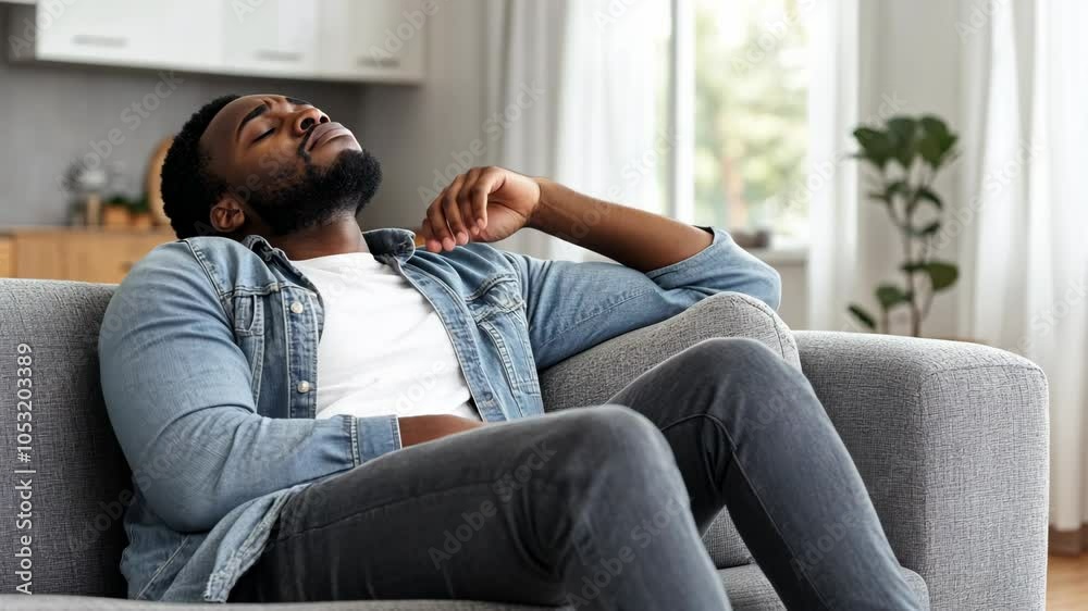 A man relaxes on a couch in his home, looking up at the ceiling A man relaxes on a couch in his home, looking up at the ceiling