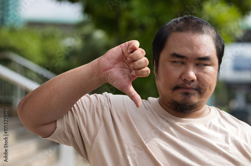 Frustrated hopeless unhappy blind man, visual-impaired middle aged asian man giving rejecting thumb down hand sign for negative, turning down hand gesture photo