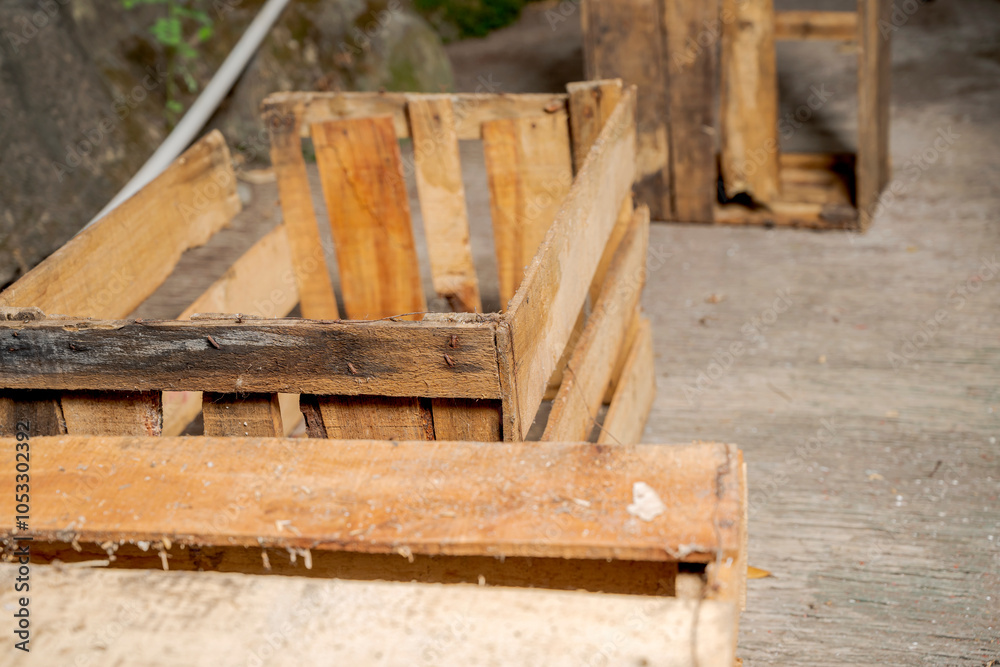 Fototapeta premium Wooden crate sitting on a concrete floor with stone wall background. Wooden pallet box