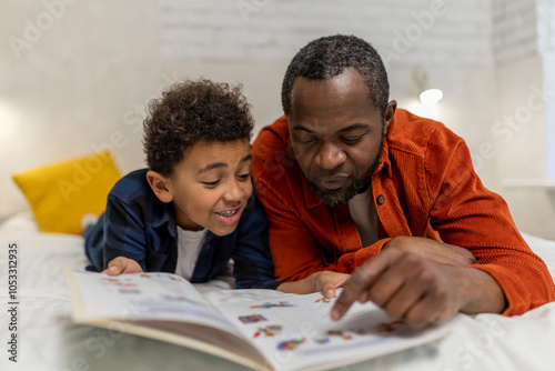 Dark-skinned man looking at the pictures in the boom together with his son photo