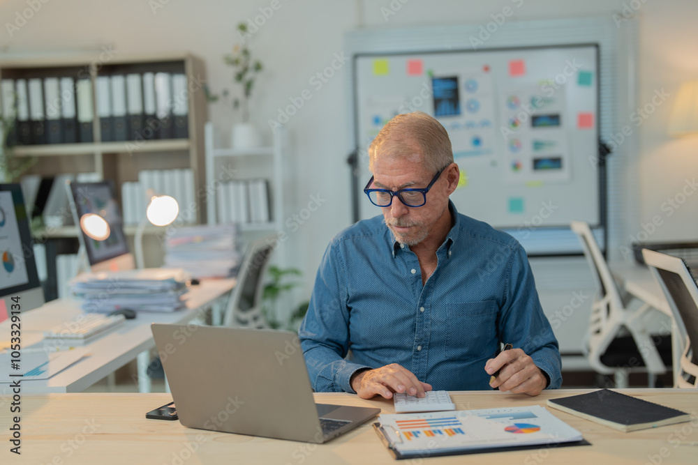 Senior business manager using calculator and laptop, analyzing financial data and reports in a bright modern office, demonstrating professionalism and expertise Senior business manager using calculator and laptop, analyzing financial data and reports in a bright modern office, demonstrating professionalism and expertise