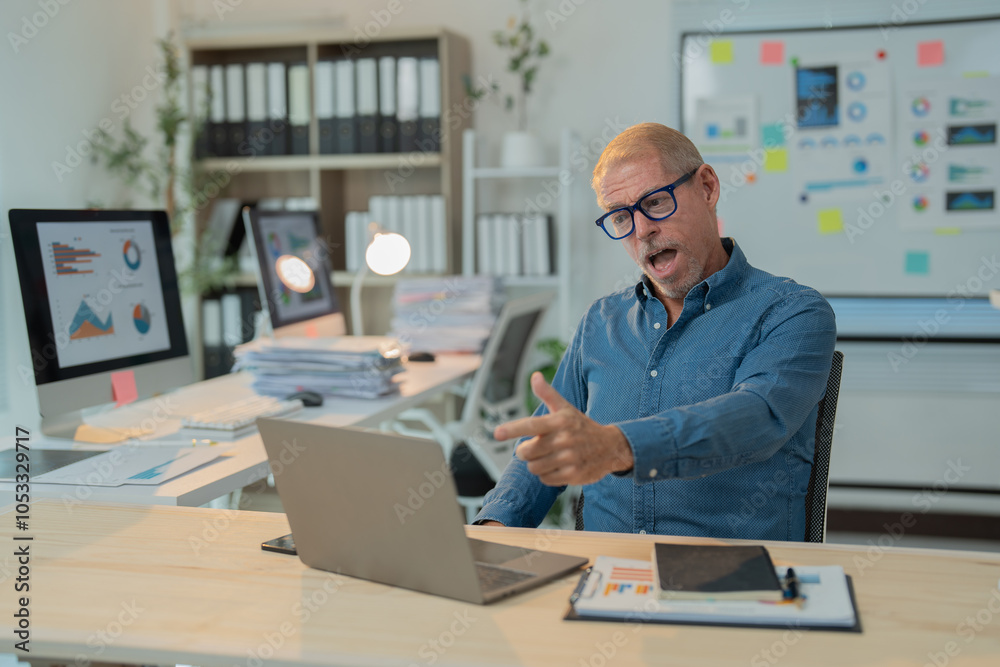 Obraz premium Surprised mature entrepreneur having video conference with colleagues on laptop, discussing project results and financial strategy, working in modern office