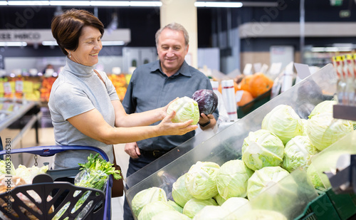 Husband and wife choose and buy fresh cabbage in grocery store photo