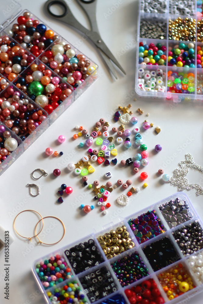 Colorful beads, letter beads, threads and other jewelry making supplies on white background. Making friendship bracelets concept. Selective focus.
