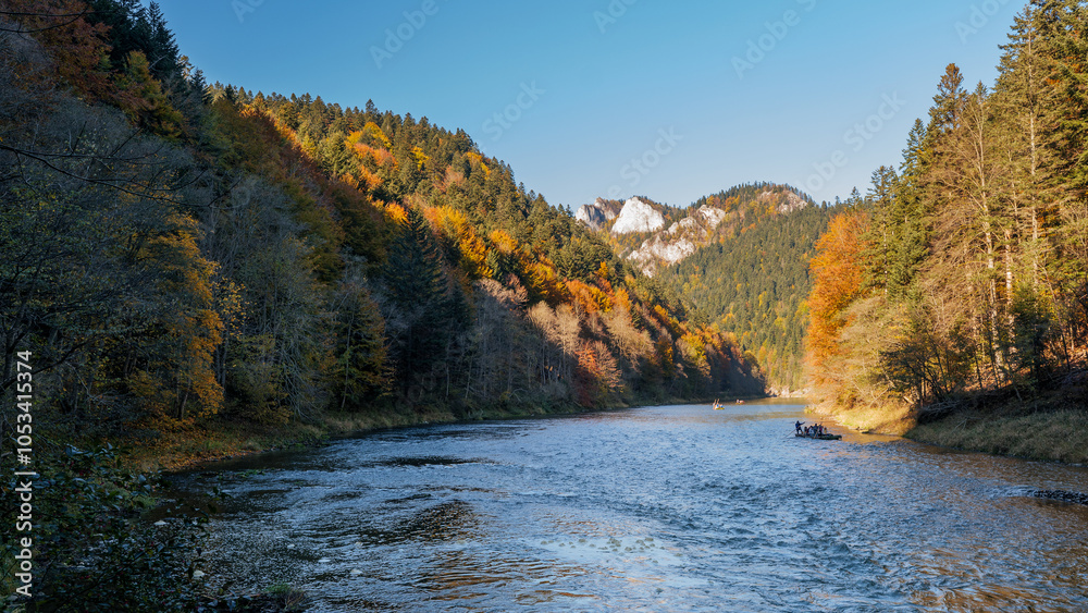 The gorge of the Dunajec River. Beautiful autumn scenery. Rafting on the Dunajec River. Colorful trees and sunlit rocky peaks. Pieniny Mountains, Poland
