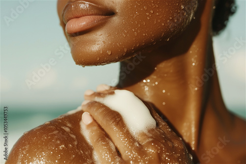 Close-up of an African American woman applying shower gel to her shoulder while taking a shower photo