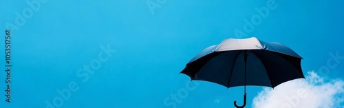 A black umbrella is suspended in a clear blue sky, contrasted by soft white clouds, evoking feelings of calm and wonder in a seemingly endless expanse