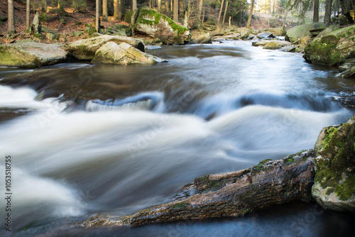 A long exposure shot of the Divoká Orlice River flowing through an autumn forest. photo