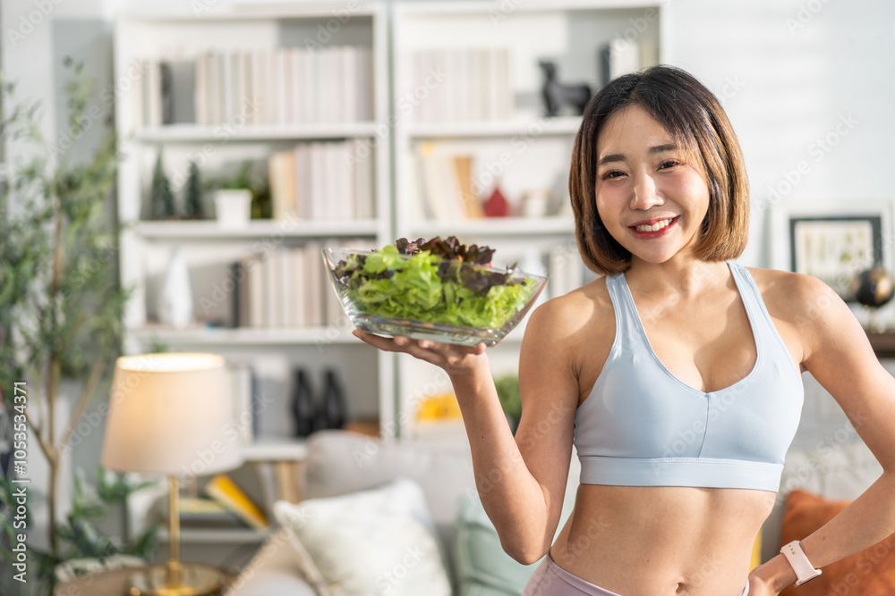 Healthy asian woman in sportswear holding fresh salad bowl at home, fitness lifestyle, healthy eating, balanced diet, wellness and nutrition concept, smiling woman enjoy healthy salad in living room Healthy asian woman in sportswear holding fresh salad bowl at home, fitness lifestyle, healthy eating, balanced diet, wellness and nutrition concept, smiling woman enjoy healthy salad in living room