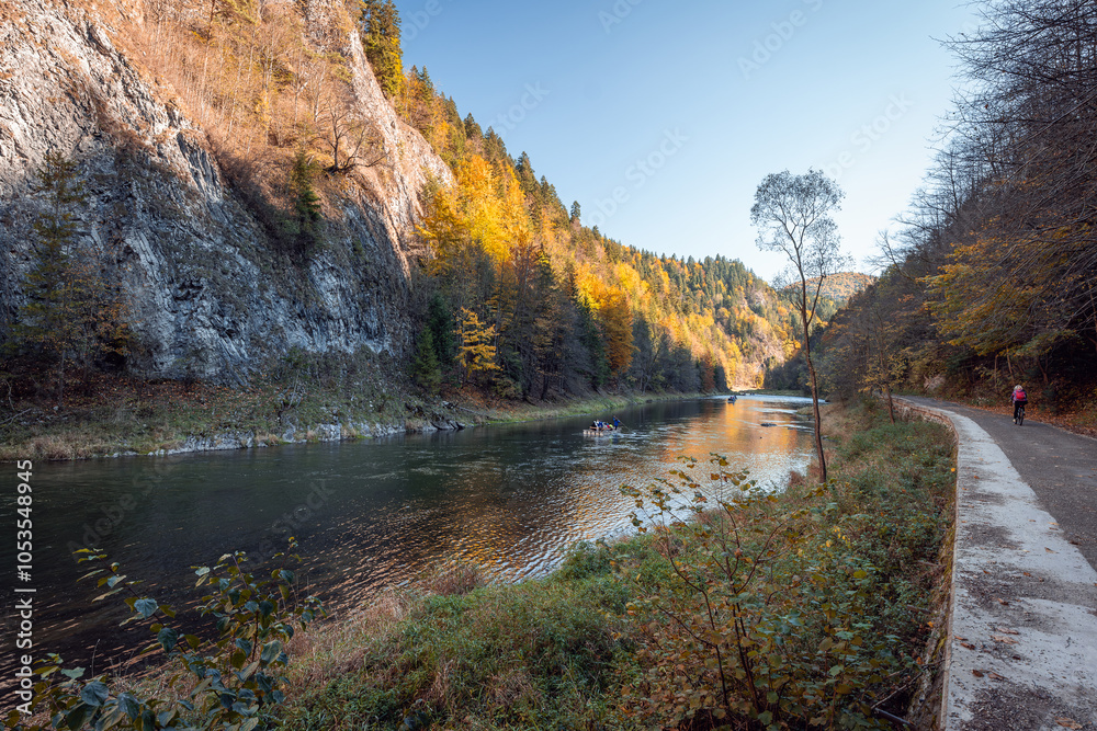 Wooden raft filled with tourists floating on the Dunajec river in the Pieniny National Park. The Dunajec Gorge in autumn. Bicycle path along the river. Traditional rafting Szczawnica, Poland
