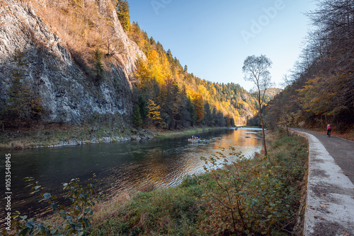 Obraz na płótnie Wooden raft filled with tourists floating on the Dunajec river in the Pieniny National Park. The Dunajec Gorge in autumn. Bicycle path along the river. Traditional rafting Szczawnica, Poland w salonie