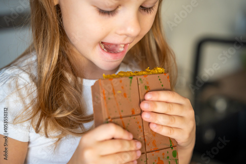 Little girl eating Dubai chocolate with pistachio paste and kataifi dough. Confectionery handmade sweets at home in the kitchen.  photo