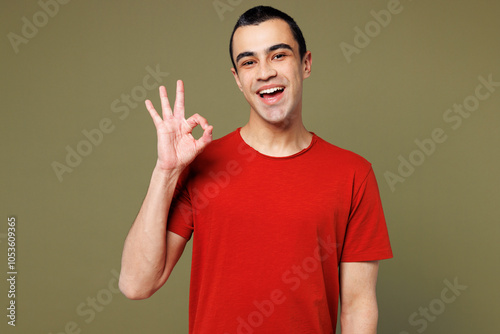 Young smiling happy satisfied cool middle eastern man he wear red t-shirt casual clothes show ok okay gesture look camera isolated on plain pastel green background studio portrait. Lifestyle concept. photo