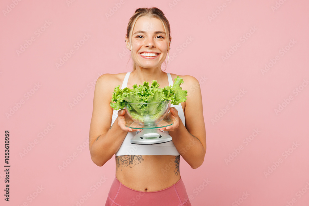 Young smiling woman wear white top casual clothes hold bunch of lettuce salad in scales bowl isolated on plain pastel light pink background Proper nutrition healthy fast food unhealthy choice concept Young smiling woman wear white top casual clothes hold bunch of lettuce salad in scales bowl isolated on plain pastel light pink background Proper nutrition healthy fast food unhealthy choice concept