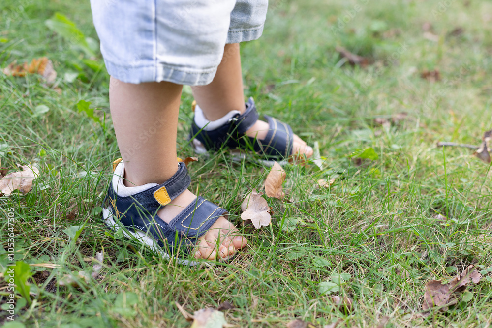 Little child walks in the park in too small sandals. Little child walks in the park in too small sandals.