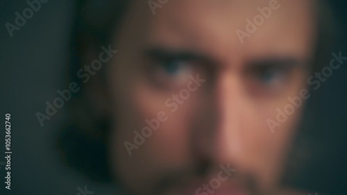 Expressive Charm  - A charismatic Slavic man with long hair and expressive big eyes, holds orange roses in front of his face, then removes the bouquet, looking directly into the camera in a close-up  photo