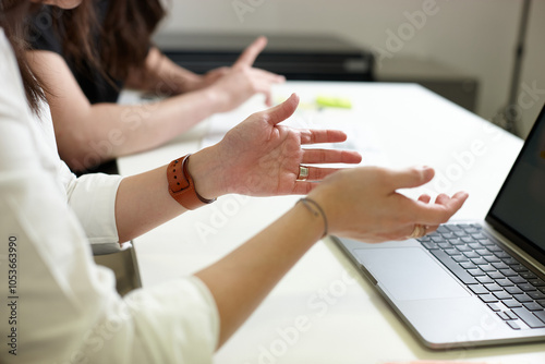 woman hands lifting on the air with red watch and a laptop on the table photo