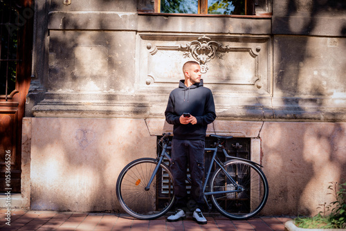 Full length of a young man standing on the street in the city and using his smarpthone photo