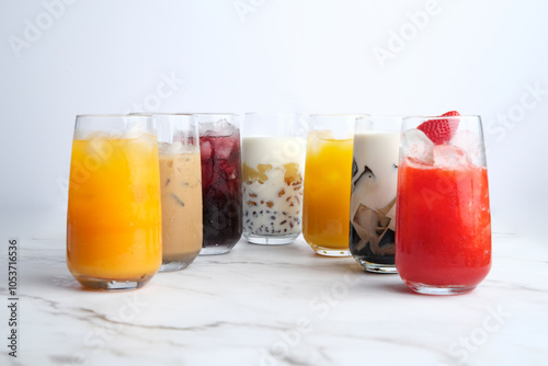 Different kinds of colorful juices in a tall glass served on a white marble countertop photo