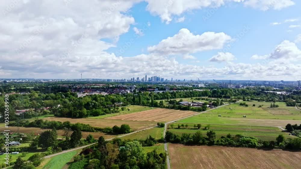Drone video of Frankfurt's skyline on a partly cloudy day, featuring the Main River in the foreground and adjacent fields. Drone move forward Drone video of Frankfurt's skyline on a partly cloudy day, featuring the Main River in the foreground and adjacent fields. Drone move forward