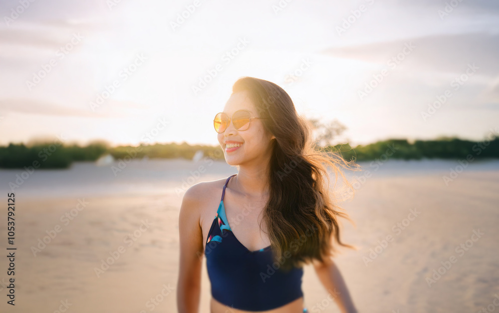 A woman in a bikini smiles and looks off to the side as she walks on ...
