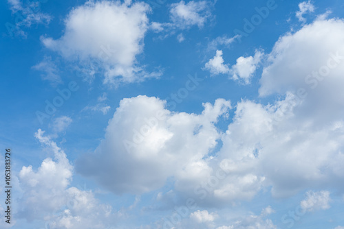 Beautiful fluffy white clouds drift across a bright blue summer sky