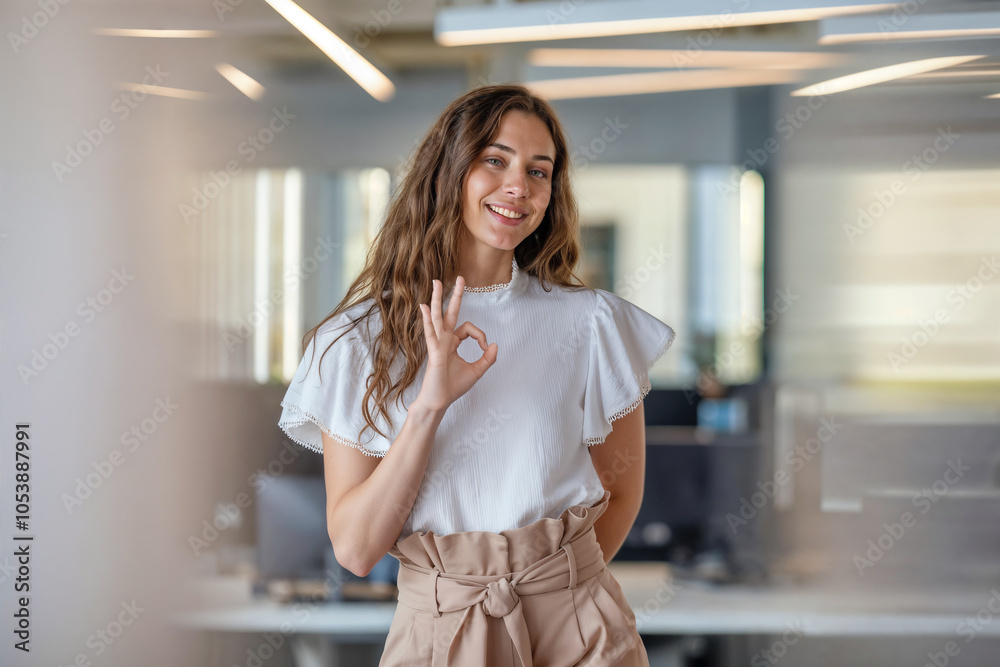 Smiling Professional Woman In Office Corridor shows „OK“ gesture Smiling Professional Woman In Office Corridor shows „OK“ gesture