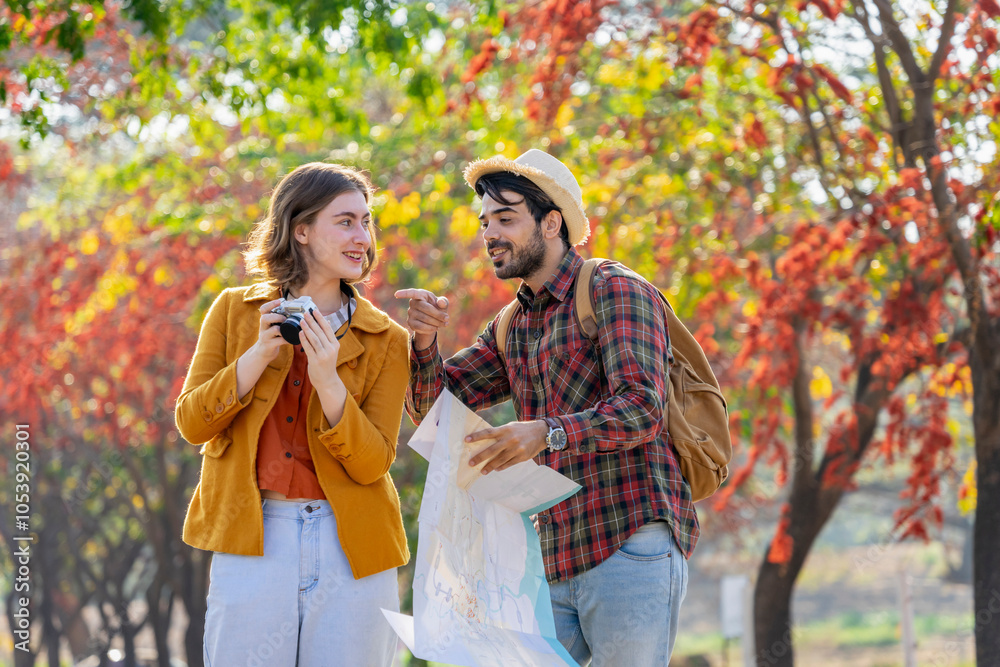 Obraz premium young caucasian couple traveling in autumn park,they are looking at a paper map for direction