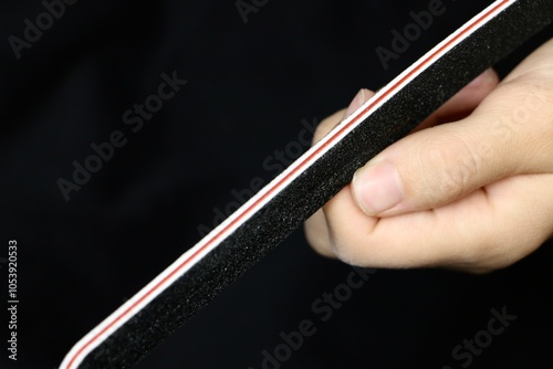 Woman files nails on a black background close-up. Nail care. Filing nails on the hands. Care about fingernails.
Women's hand with natural nails