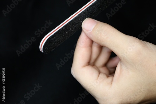 Woman files nails on a black background close-up. Nail care. Filing nails on the hands. Care about fingernails.
Women's hand with natural nails